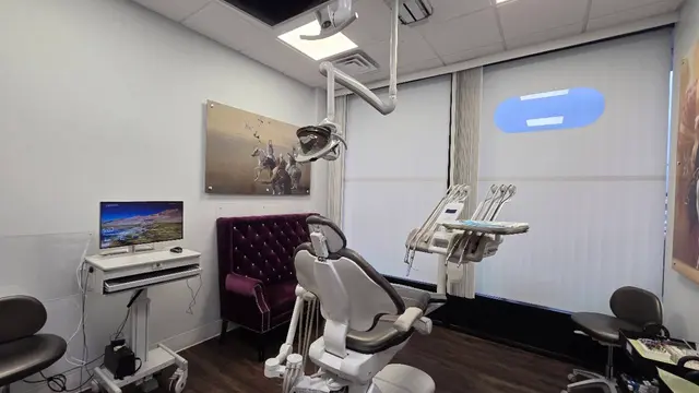 Treatment room at Ayat Dental with a dental chair and burgundy seating